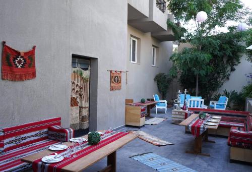 a patio with red benches and tables and chairs at Aitch Boutique Hotel - an LIH Hotel in Madaba