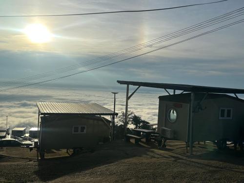 a shed and a building with the sun in the sky at สเตชั่นภูทับเบิก-บ้านดาดฟ้าทะเลหมอก in Ban Tha Kok Hai