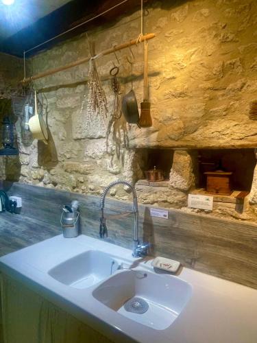 - un évier dans la cuisine dotée d'un mur en pierre dans l'établissement Les Galineaux, à La Roquille