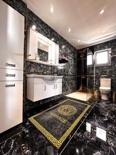 a bathroom with black marble walls and a sink and a toilet at Long Beach Rental Apartments in Trikomo