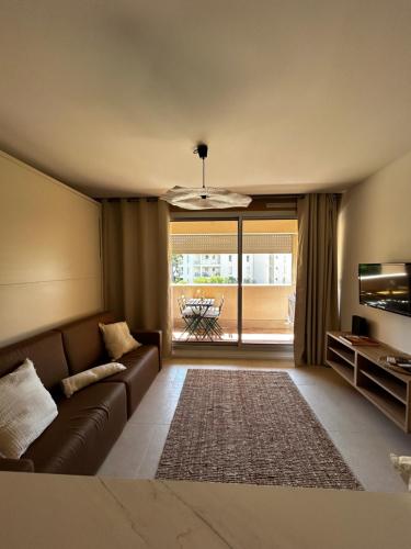 un salon avec un canapé et une grande fenêtre dans l'établissement Studio Port de Hyeres Plage et Piscine, à Hyères