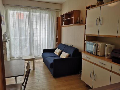 un salon avec un canapé bleu et un four micro-ondes dans l'établissement Studette meublée, Ranelagh Paris 16e, à Paris