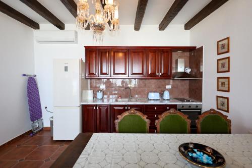 a kitchen with wooden cabinets and a white refrigerator at Sunrise House - Swimming Pool in Berat