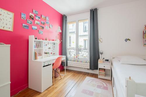 - une chambre aux murs roses avec un bureau et un lit dans l'établissement Veeve - Parisian Vistas, à Paris