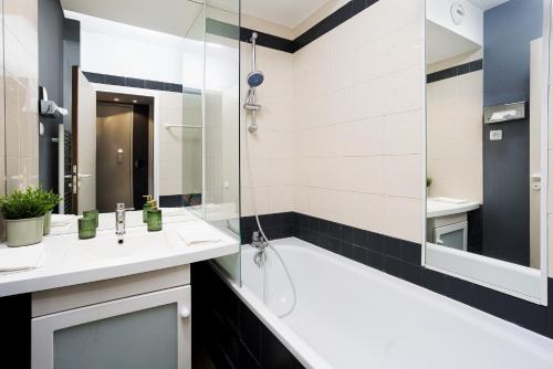 une salle de bain avec une baignoire, un lavabo et un miroir dans l'établissement Lila Home - Confortable studio in Paris, à Paris
