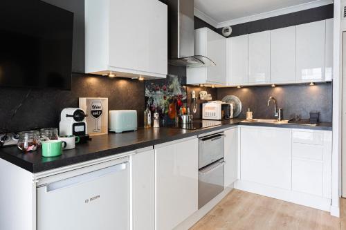 une cuisine avec des armoires blanches et un comptoir noir dans l'établissement Lila Home - Confortable studio in Paris, à Paris