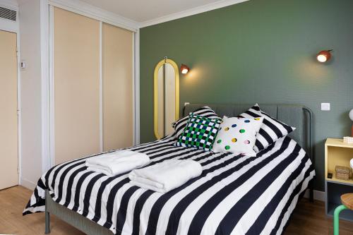 - une chambre avec un lit noir et blanc et des oreillers dans l'établissement Lila Home - Confortable studio in Paris, à Paris