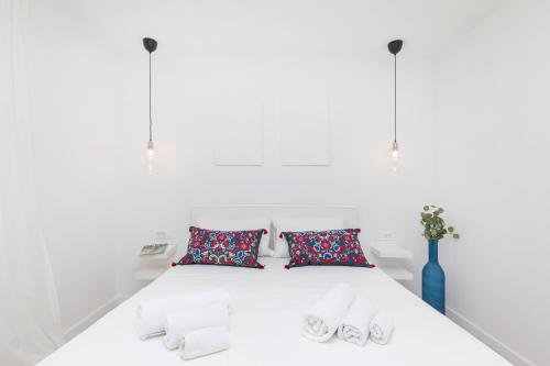 a white bed with two pillows and a blue vase at House Aqua in Mlini