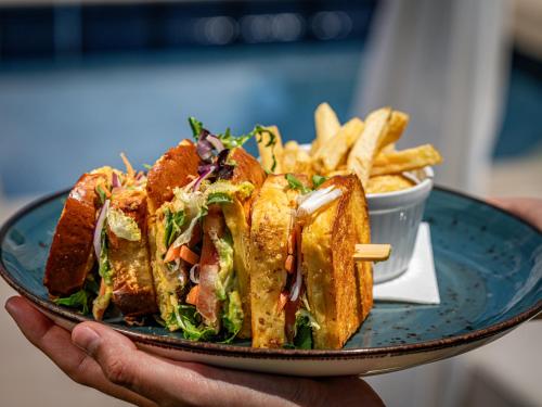 a person holding a plate with a sandwich and french fries at Es Figueral Nou Hotel Rural & Spa - Adults Only - Over 12 in Montuiri