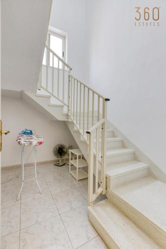 a staircase in a white room with a table at Spacious 4BR Terraced House with Rooftop Access by 360 Estates in Marsaskala