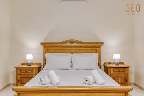 a bedroom with a bed with two pillows and two lamps at Spacious 4BR Terraced House with Rooftop Access by 360 Estates in Marsaskala