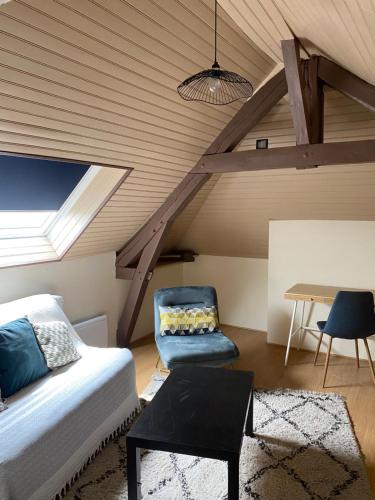 a attic room with a bed and a chair and a table at Charmante Maison Normande in Saint-Julien-de-la-Liègue