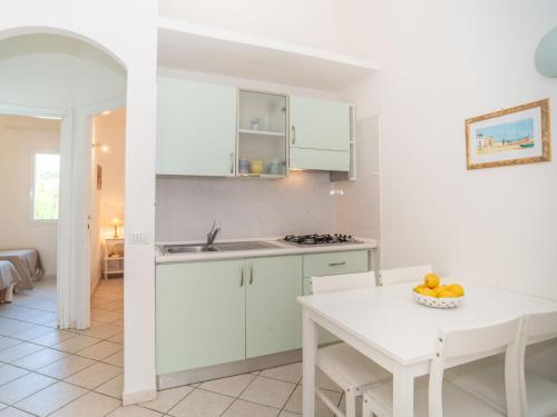 a kitchen with white cabinets and a white table at Apartment Residenza Mediterranea-3 by Interhome in Cannigione