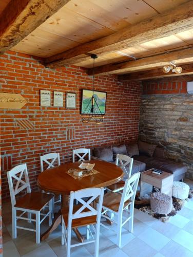 a dining room with a table and chairs and a brick wall at Etno kuća Ostrvica in Varnice