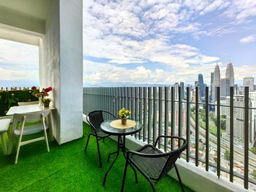 a balcony with a table and chairs and a view of the city at The Luxe Colony KLCC By AZHA in Kuala Lumpur