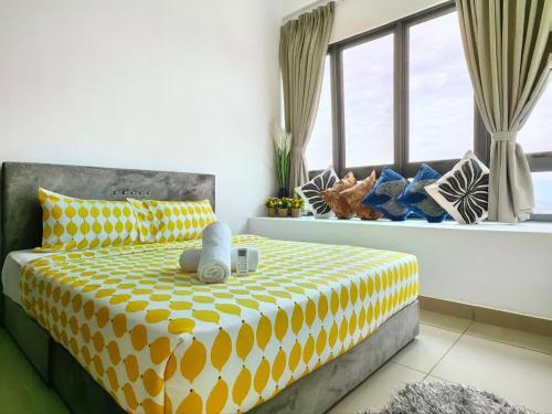 a bedroom with a yellow and white bed with windows at The Luxe Colony KLCC By AZHA in Kuala Lumpur