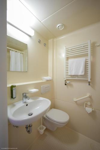 a white bathroom with a sink and a toilet at Hotel Luise in Bad Bergzabern