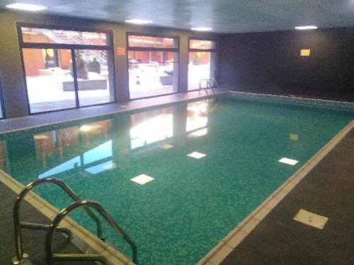 a large swimming pool with green water in a building at Résidence Le Pic de l'Ours in Font-Romeu