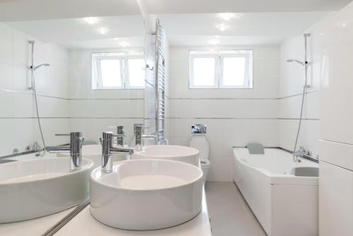 a white bathroom with two sinks and a tub at Apartment 18 in Belgrade