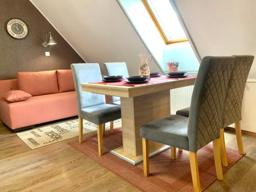 a dining room table with two chairs and a couch at KisPagony Apartman in Kaposvár