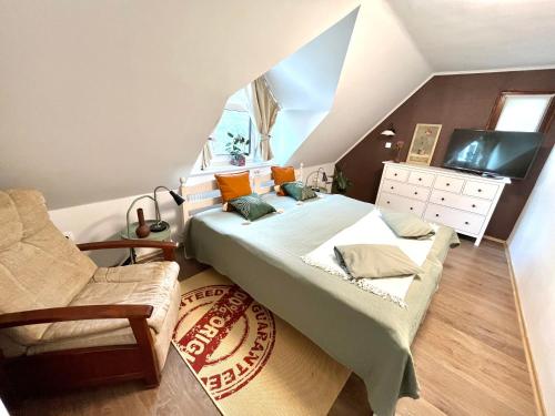a attic bedroom with two beds and a chair at KisPagony Apartman in Kaposvár