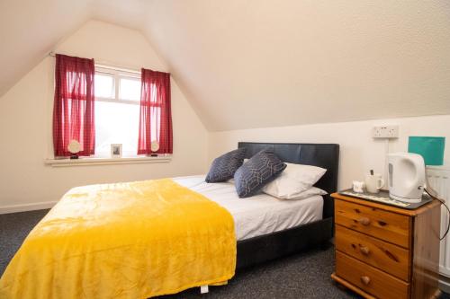 a bedroom with a bed with a yellow blanket and a window at Pebbles guest house quad room 10 in Southampton