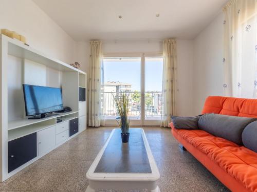 ein Wohnzimmer mit einem orangenen Sofa und einem TV in der Unterkunft Apartment Cesar by Interhome in Cunit