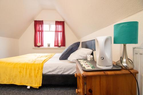 a bedroom with a bed and a lamp on a table at Pebbles guest house quad room 10 in Southampton