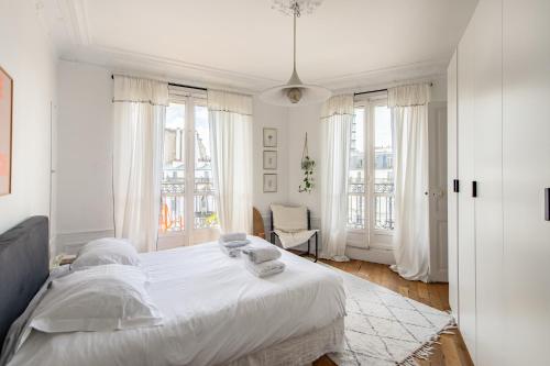 - une chambre blanche avec un grand lit et des fenêtres dans l'établissement Faidherbe-Superbe duplex proche Bastille, à Paris