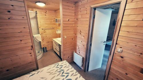 a small bathroom with wooden walls and a bed and a shower at Camp Ante-Gojko in Grebaštica