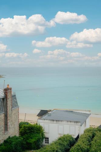 un bâtiment blanc à côté d'une plage avec une maison dans l'établissement Apartment Le Cap Fréhel by Interhome, à Dinard