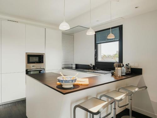 une cuisine avec des armoires blanches et un comptoir avec des tabourets dans l'établissement Apartment Le Cap Fréhel by Interhome, à Dinard
