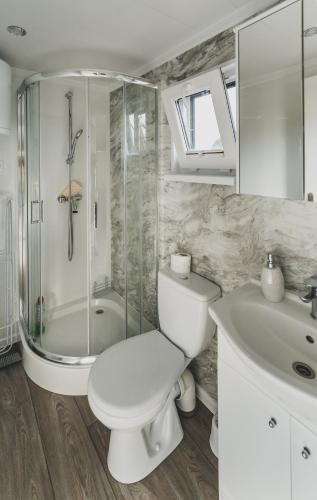 a bathroom with a toilet and a sink and a shower at Lawendowy Zakątek 3 domek z balią in Sominy