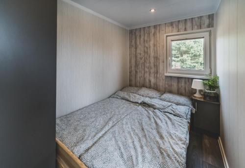 a small bedroom with a bed and a window at Lawendowy Zakątek 3 domek z balią in Sominy