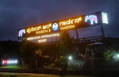 a sign that is lit up at night at NAVARATHNA International resort in Sollebail