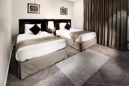 a hotel room with two beds and a rug at Aswar Al olaya for serviced Apartments in Al Khobar