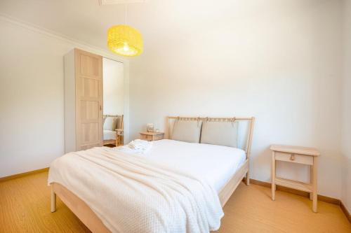 a white bedroom with a bed and two tables at GuestReady - Casa de Nazaré da Galileia in Quinta do Anjo