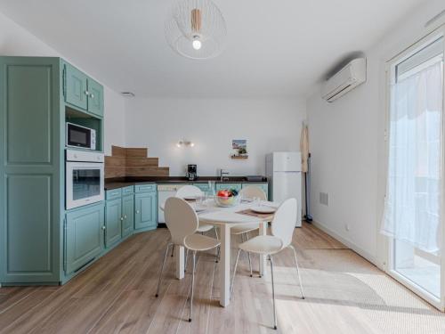 une cuisine avec des placards verts ainsi qu'une table et des chaises blanches dans l'établissement Apartment Pine's Mansion-1 by Interhome, au Barcarès