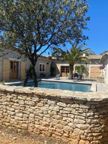 un mur en pierre avec un arbre devant une maison dans l'établissement Maison en pierre, à Grignan