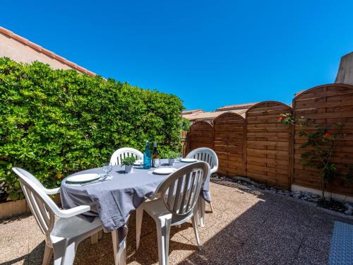 une table avec quatre chaises blanches et une clôture dans l'établissement Holiday Home Le Hameau des Pêcheurs by Interhome, à Port-Leucate
