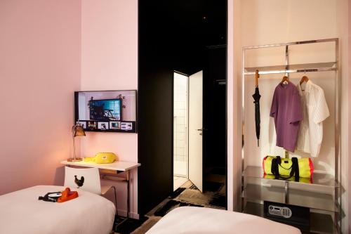 a bedroom with two beds and a desk and a mirror at Mama Shelter Bordeaux Centre in Bordeaux