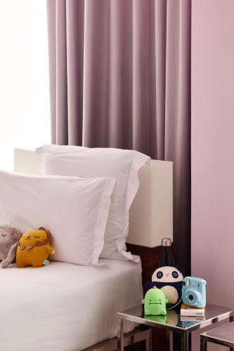 a bed with white sheets and stuffed animals on it at Mama Shelter Bordeaux Centre in Bordeaux