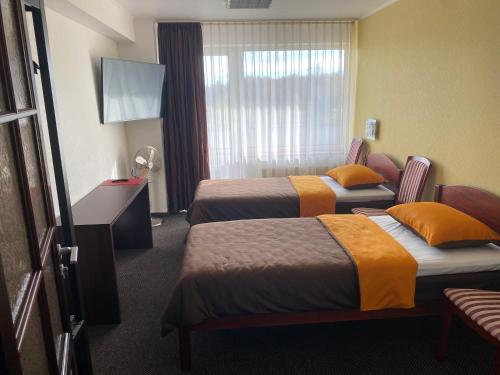 a hotel room with two beds and a television at Baskervilu Muiža in Sērenes