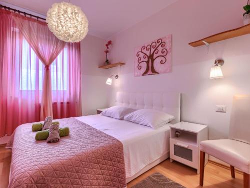 Un dormitorio con una cama blanca y cortinas rosas. en Apartment Apartmani Amaii-1 by Interhome, en Karigador