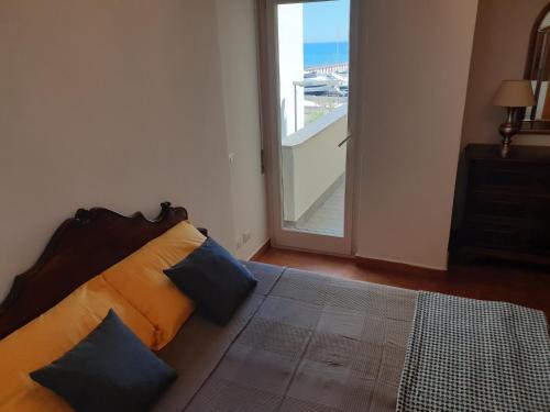 a bedroom with a bed with pillows and a balcony at Nettuno apartment city center sea view in Nettuno