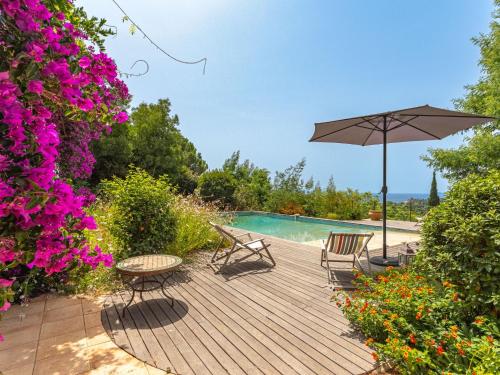- une terrasse en bois avec des chaises et un parasol à côté de la piscine dans l'établissement Villa Villa du Temple by Interhome, au Lavandou