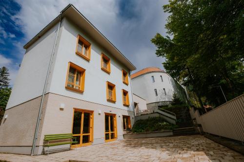 a white house with a green bench in front of it at Szent Anna Vendégház in Băile Tuşnad