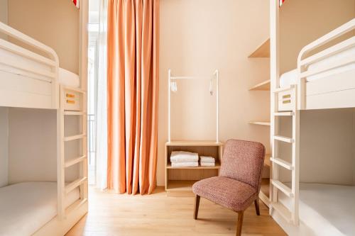 a bedroom with two bunk beds and a chair at Villa Camille Hotel & Spa in Banyuls-sur-Mer