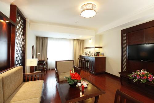 a living room with a couch and a television and a table at Majestic Mong Cai Hotel in Móng Cái