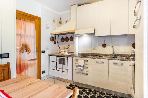 a kitchen with white cabinets and a wooden table at Appartamento Vioz in Peio